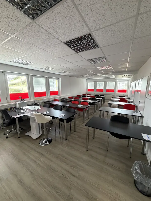 Schulraum mit Dozentenplatz links und langen Tischreihen